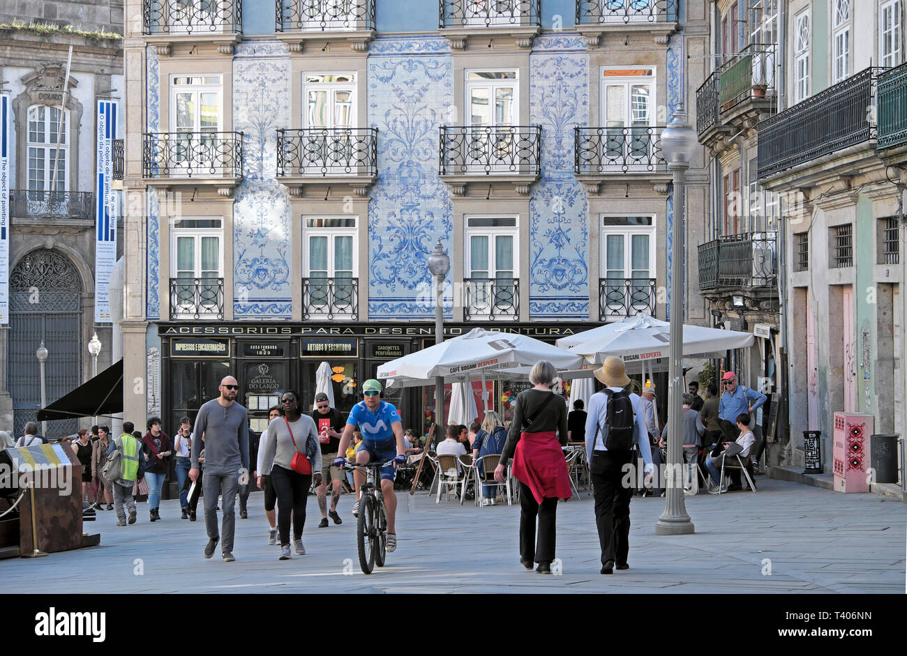 Radfahrer reiten Fahrrad entlang der Rua das Flores Vergangenheit Gebäude mit blauen azulejos Fliesen, Restaurant und Touristen auf der Straße Porto Portugal Europa KATHY DEWITT Stockfoto