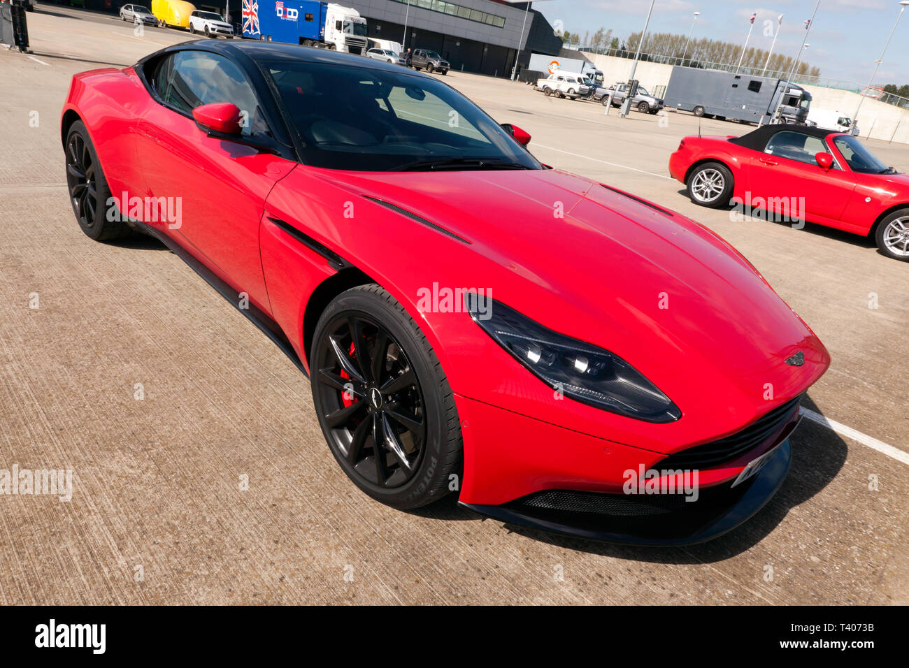 Eine rote, Aston Martin DB11, in der Internationalen Fahrerlager geparkt, während der 2019 Silverstone Classic Media Day Stockfoto