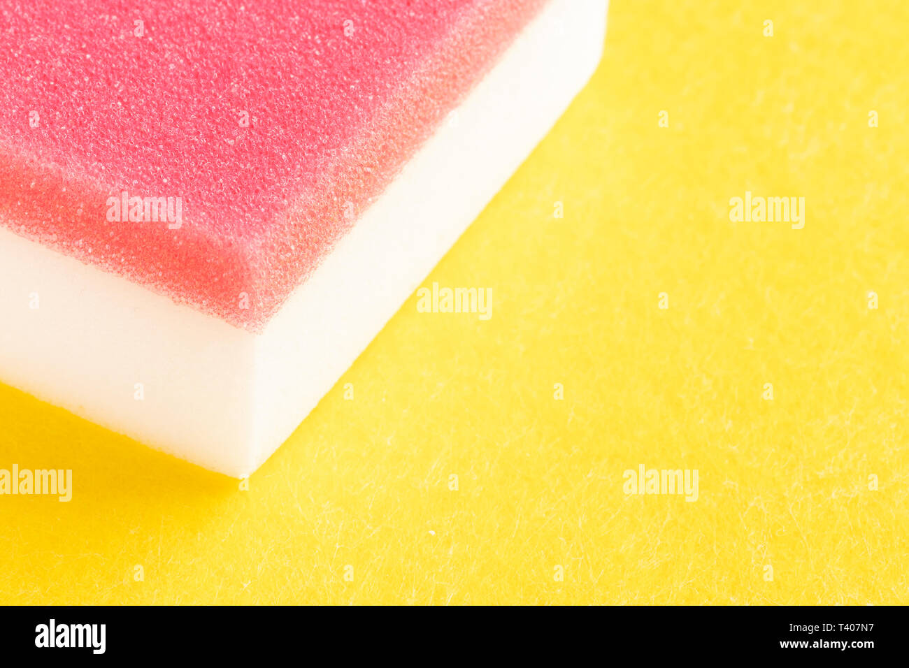 Rot-weißer Schwamm zum Waschen auf Gelb. Freier Speicherplatz für Inschriften und Design Stockfoto