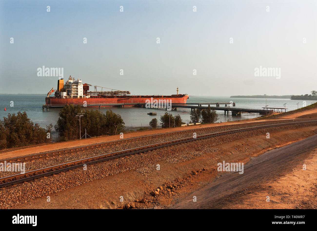 Port Operations für den Transport von Eisenerz. Über erz Zug Schiene Schleife TSV Schiff vertäut am Steg layby, bevor Sie zu laden. Stockfoto