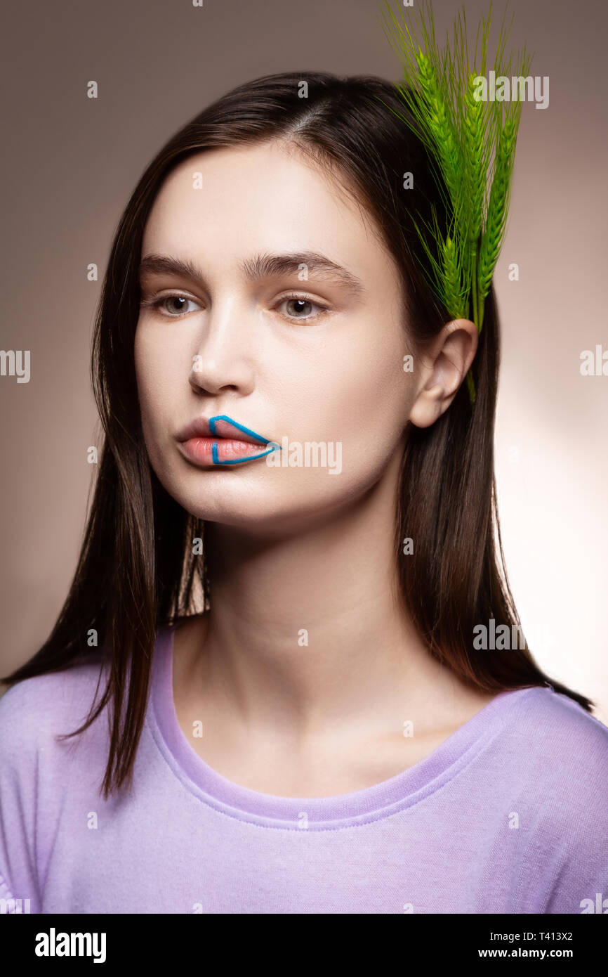Dunkelhaarige Model posiert mit grünen Ährchen im Haar Stockfoto