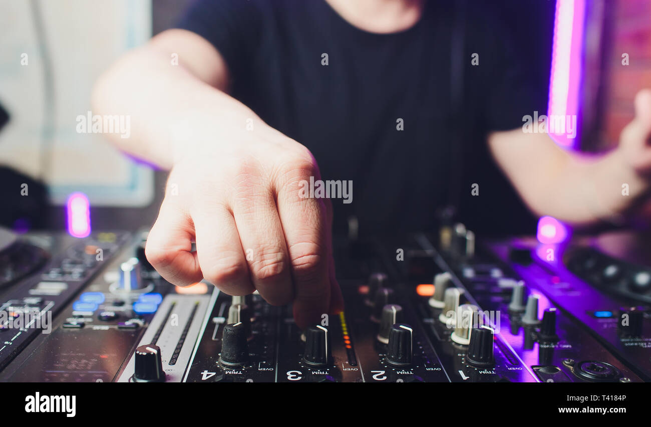 Nahaufnahme der Hände der männlichen disc jockey Mischen Musik auf seinem Deck mit seinen Händen über die Schallplatte auf den Plattenteller und die Kontrolle balanciert Stockfoto