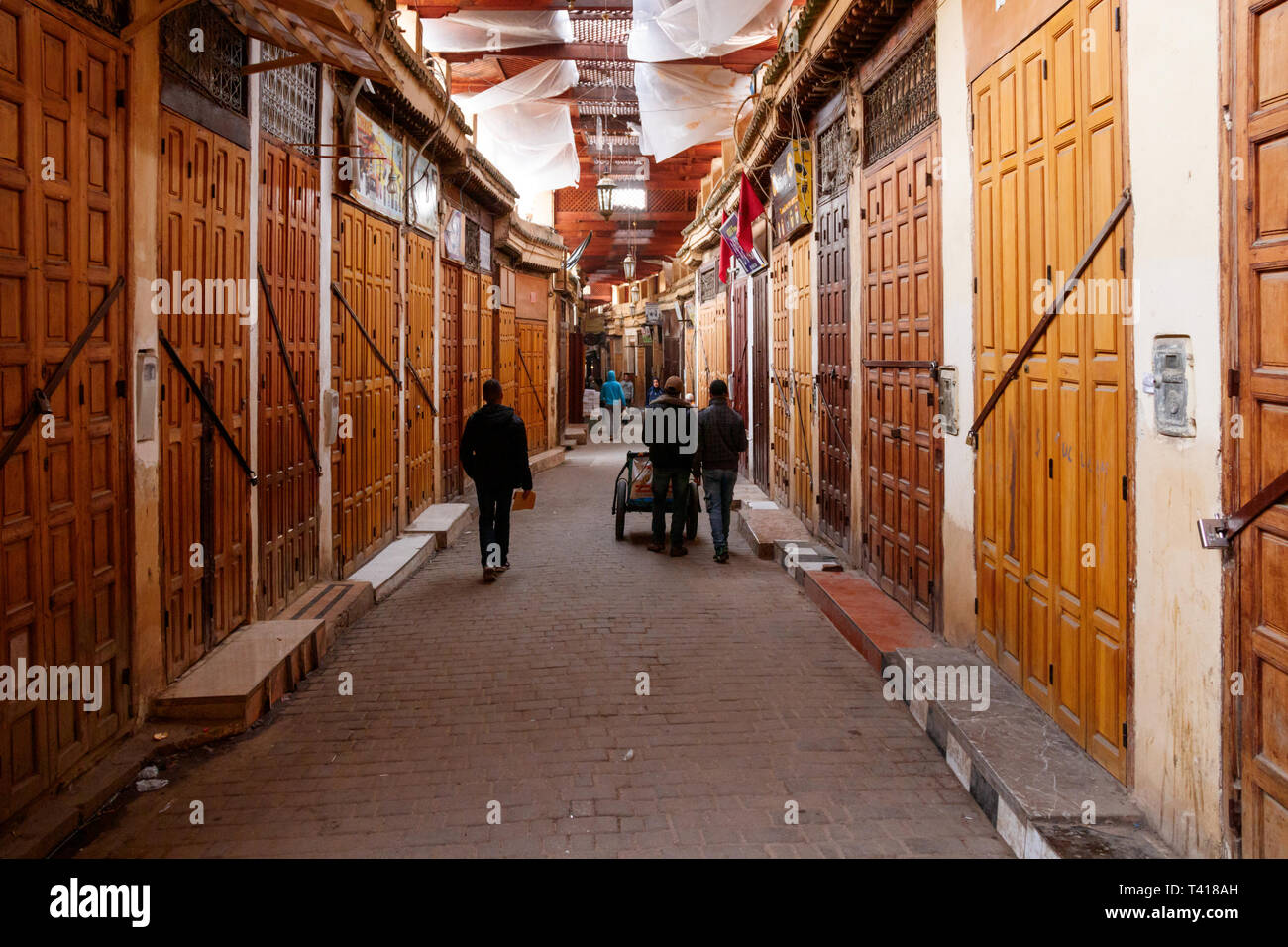 Unbekannte Menschen zu Fuß in der alten Medina entlang der verschlossenen Türen der zahlreiche Geschäfte. Fez, Marokko. Stockfoto