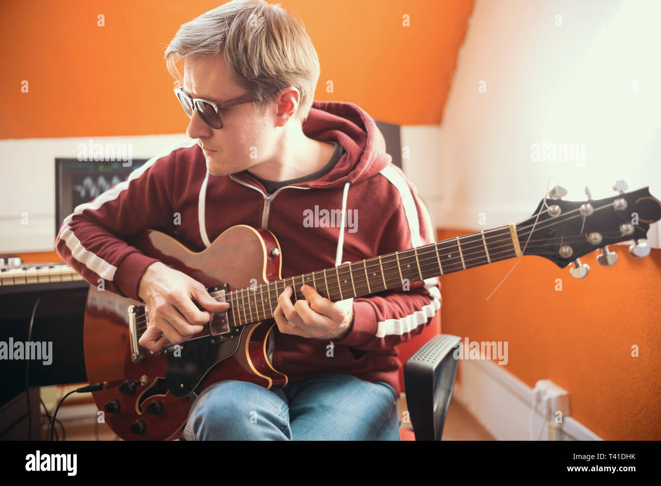 Ein Musiker Mann in Gläser, Gitarre zu spielen und mit der Aufnahme eines Songs im Studio Stockfoto