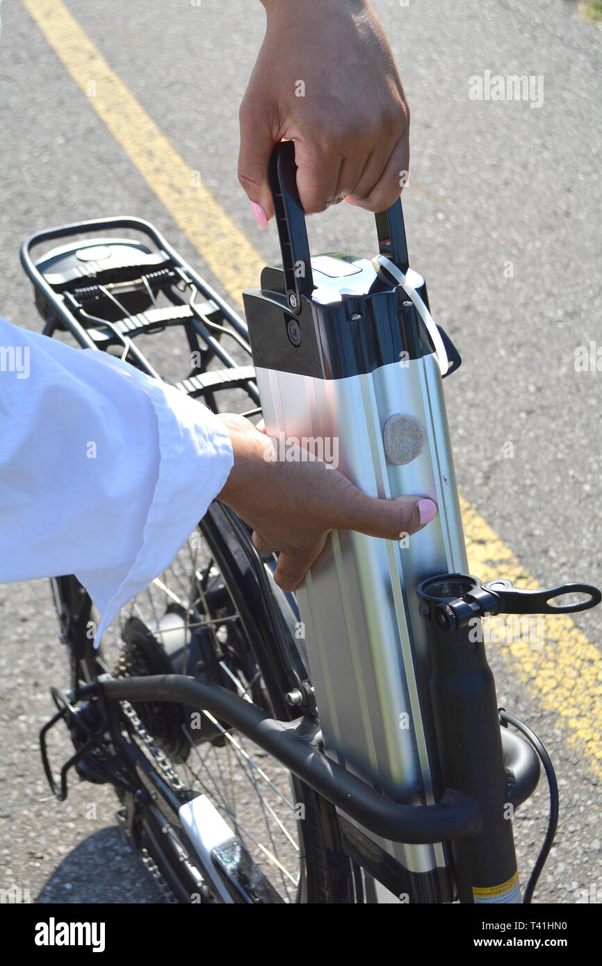 Frauen, die sich in der Batterie Pack mit dem Fahrrad in der Nähe von ihr  e-Bike. Weiblich, aus e Fahrrad Akku. Sichtbar Motor und Getriebe auf dem  Hinterrad. Ökologie c Stockfotografie -