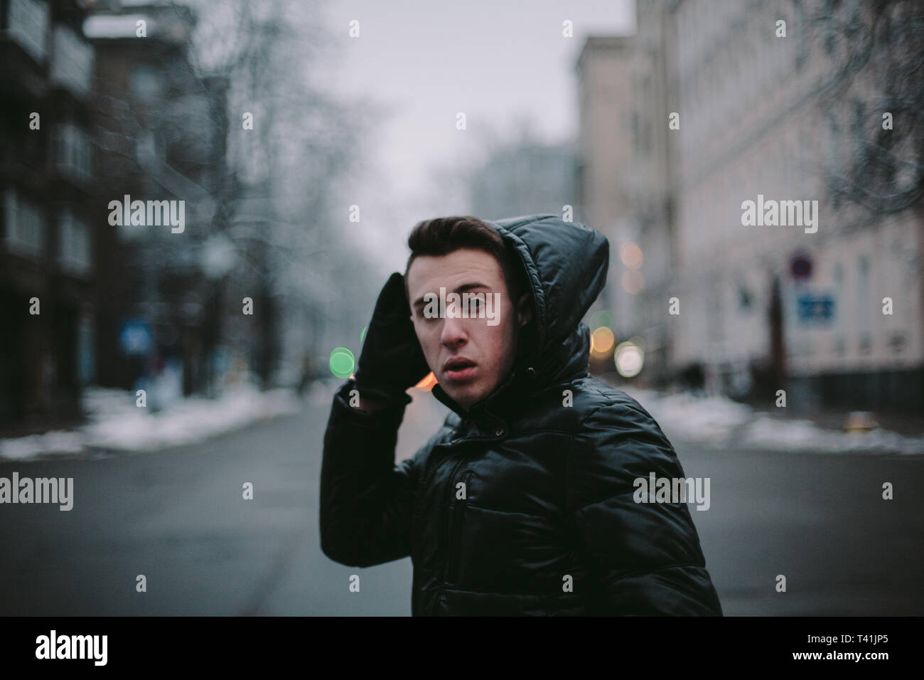 Junger Mann Kreuzung Straße in der Stadt im Winter Stockfoto