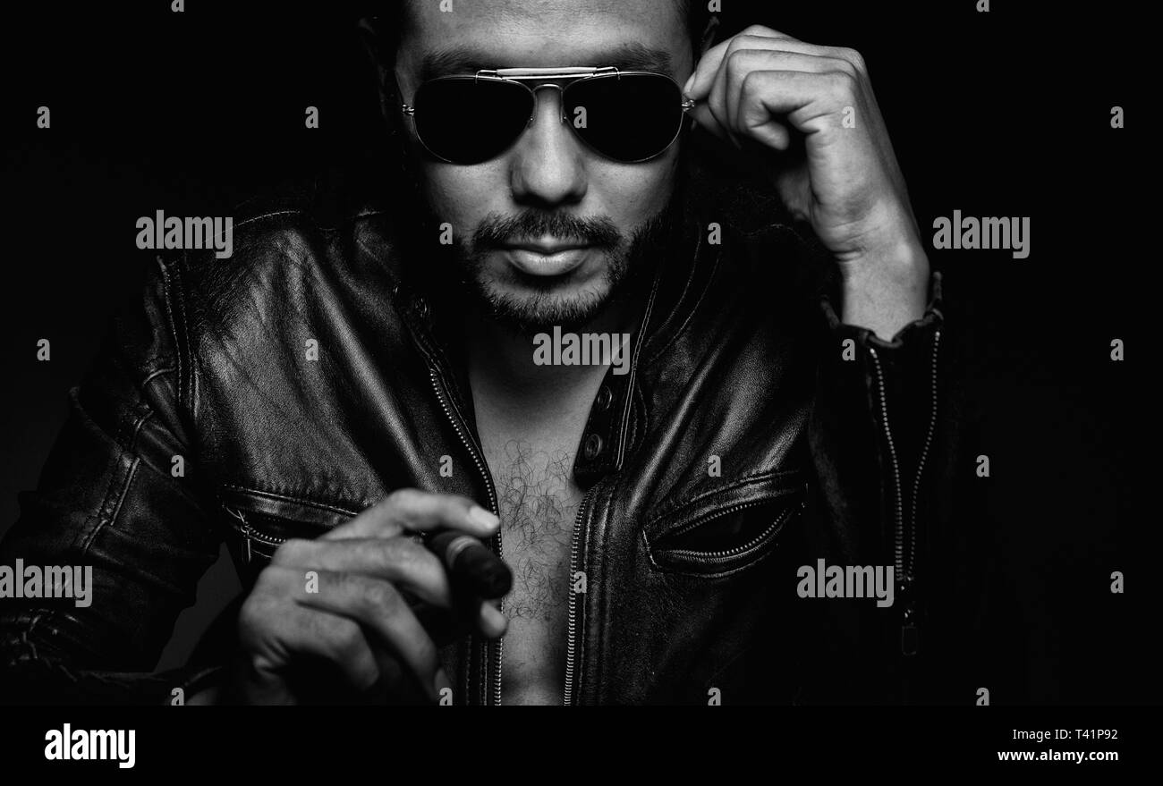 Mann, der Sunglases und schwarze Jacke und Rauch Stockfoto