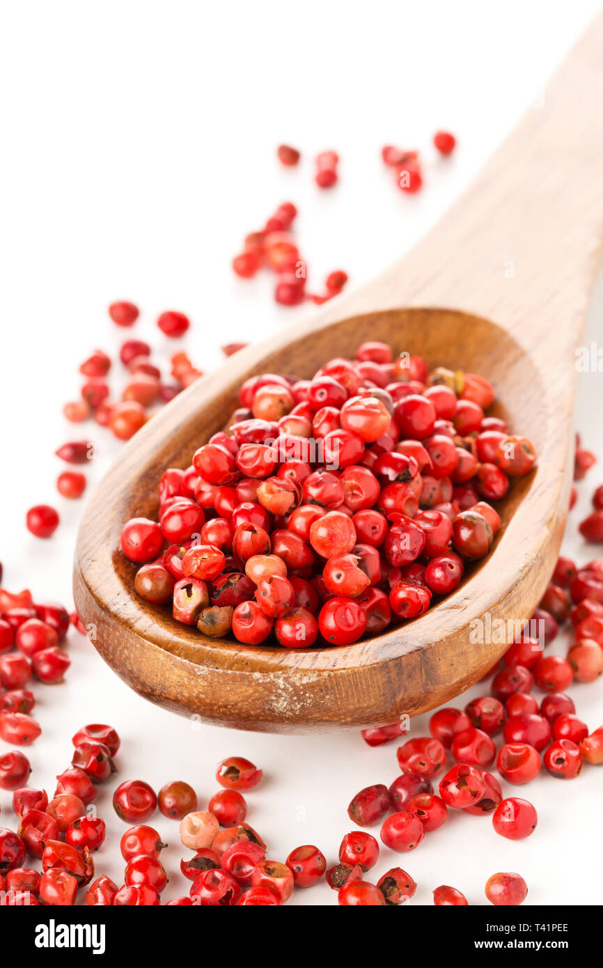 Pink oder Rosa brasilianischen roter Pfeffer (Schinus terebinthifolius) Löffel aus Holz mit weißem Hintergrund Stockfoto