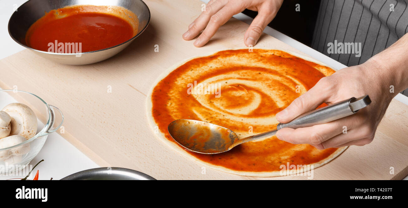 Koch Verbreitung Tomatenmark auf Pizza base Stockfoto