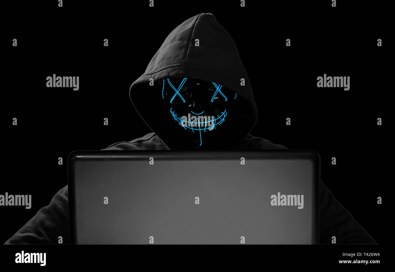 Hacker mit glühenden Maske hinter Notebook Laptop vor isolierten schwarzen Hintergrund internet Cyber Attack computer concept Hack Stockfoto