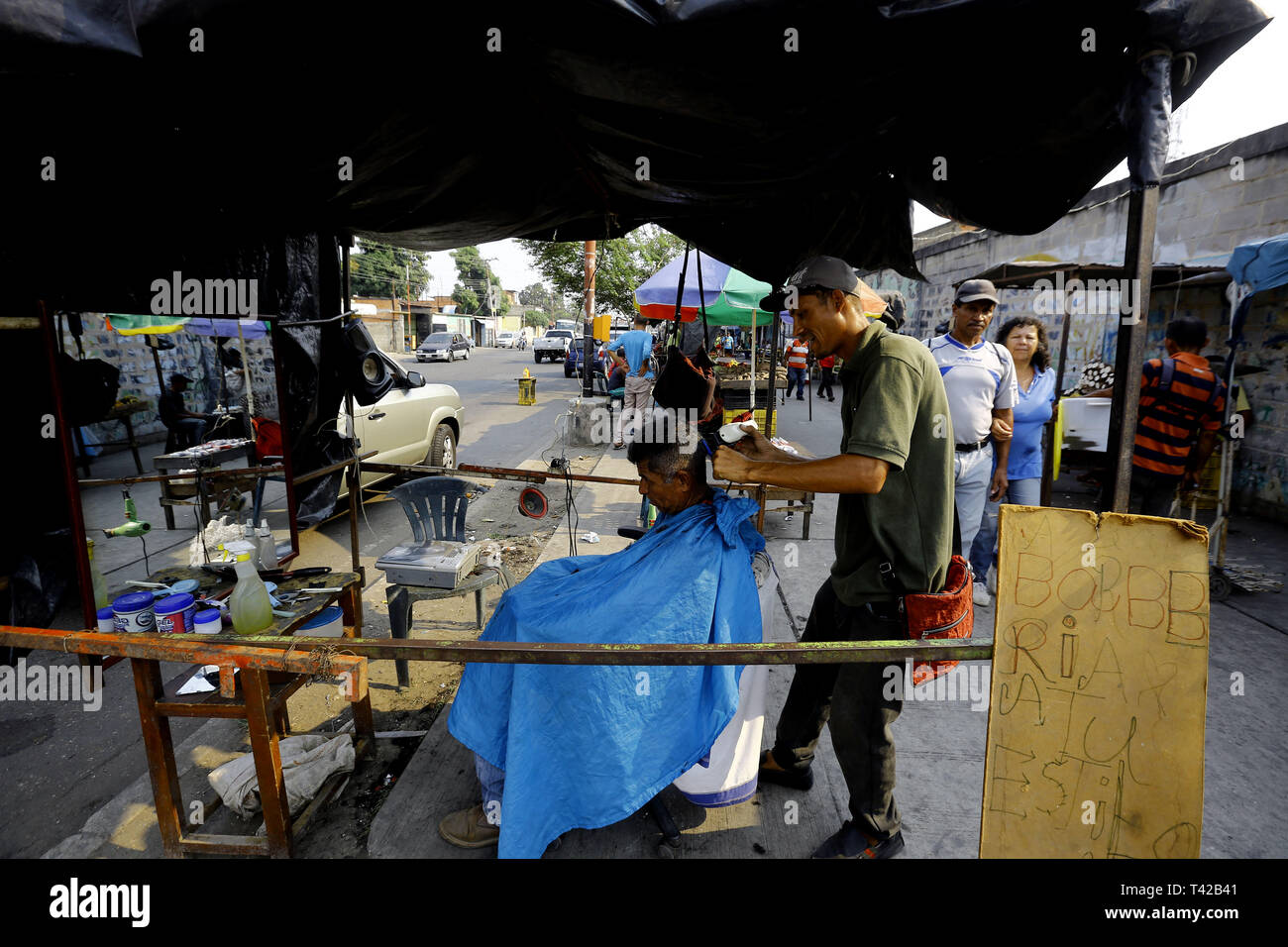 Valencia, Carabobo, Venezuela. 11 Apr, 2019. Pril 11, 2019. Gregory Hernandez, ist eine junge Venezolanische, die nicht mehr einen Job als Maurer, der seit vielen Jahren gewidmet war, beschlossen, eine lokale Straße, zu improvisieren und der Friseur- Service an solicarios Preise anbieten, die nach seinen eigenen Worten mindestens hilft Essen für Ihre Familie erhalten. Akzeptiert abgesehen von Bargeld oder elektronisches Geld, Pakete von Reis, Brot, Mehl, Teigwaren und anderen Lebensmitteln. Das Foto wurde auf Arantzasu Avenue, südlich der Stadt Valencia, Carabobo Zustand. Foto: Juan Carlos Hernandez (Credit Bild: © Juan Carlos Stockfoto