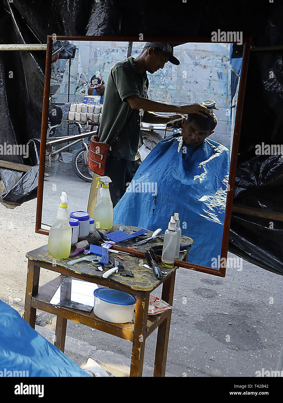 Valencia, Carabobo, Venezuela. 11 Apr, 2019. Pril 11, 2019. Gregory Hernandez, ist eine junge Venezolanische, die nicht mehr einen Job als Maurer, der seit vielen Jahren gewidmet war, beschlossen, eine lokale Straße, zu improvisieren und der Friseur- Service an solicarios Preise anbieten, die nach seinen eigenen Worten mindestens hilft Essen für Ihre Familie erhalten. Akzeptiert abgesehen von Bargeld oder elektronisches Geld, Pakete von Reis, Brot, Mehl, Teigwaren und anderen Lebensmitteln. Das Foto wurde auf Arantzasu Avenue, südlich der Stadt Valencia, Carabobo Zustand. Foto: Juan Carlos Hernandez (Credit Bild: © Juan Carlos Stockfoto