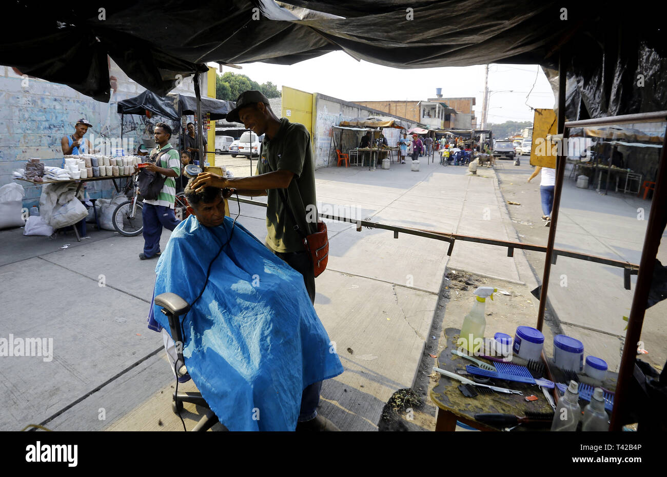 Valencia, Carabobo, Venezuela. 11 Apr, 2019. Pril 11, 2019. Gregory Hernandez, ist eine junge Venezolanische, die nicht mehr einen Job als Maurer, der seit vielen Jahren gewidmet war, beschlossen, eine lokale Straße, zu improvisieren und der Friseur- Service an solicarios Preise anbieten, die nach seinen eigenen Worten mindestens hilft Essen für Ihre Familie erhalten. Akzeptiert abgesehen von Bargeld oder elektronisches Geld, Pakete von Reis, Brot, Mehl, Teigwaren und anderen Lebensmitteln. Das Foto wurde auf Arantzasu Avenue, südlich der Stadt Valencia, Carabobo Zustand. Foto: Juan Carlos Hernandez (Credit Bild: © Juan Carlos Stockfoto