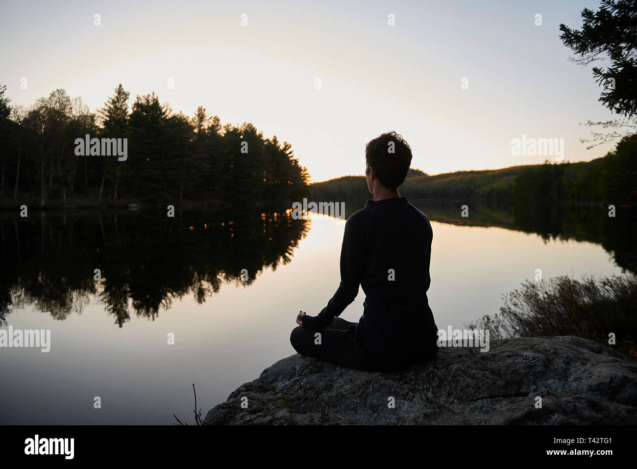 Frau sitzt im Schneidersitz durch einen See zu meditieren, Quebec, Kanada Stockfoto