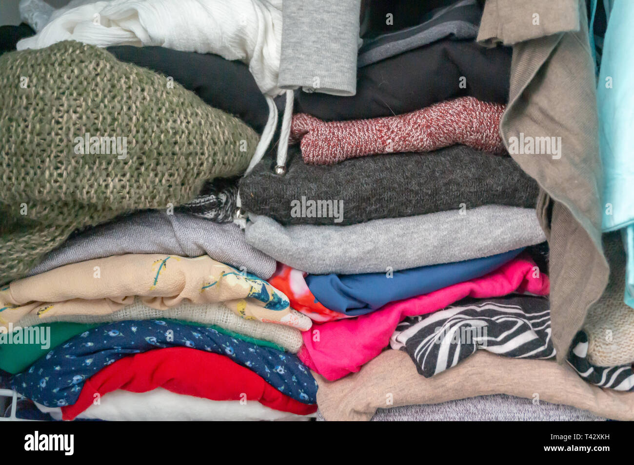 Crammed gefaltet Pullover und Kleider einer Frau in einem Schrank. Darstellung über die Notwendigkeit, für Schrank Organisation, aufräumen, Spenden. Stockfoto