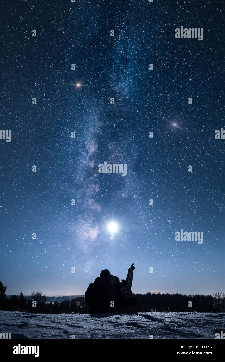Silhouette von ein paar sitzen auf Schnee im winter nacht und der Mond und die Sterne. Stockfoto