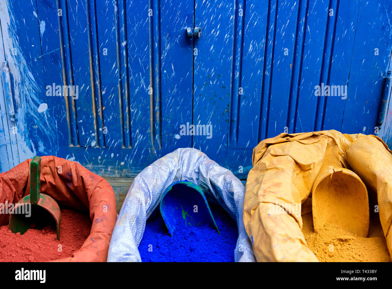 Taschen von bunten Farbe pulverbeschichtet (Pigment Pulver) in den Primärfarben vor blauem Hintergrund Stockfoto