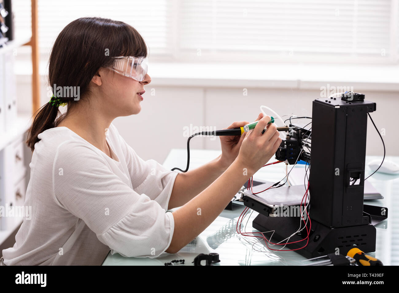 Junge weibliche Techniker tragen Sicherheit Brillen mit Lötkolben Stockfoto