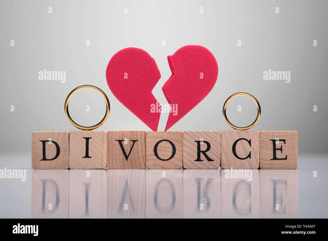 Verlobungsring und gebrochenes Herz Form über Scheidung Text Holzklotz gegen grauer Hintergrund Stockfoto