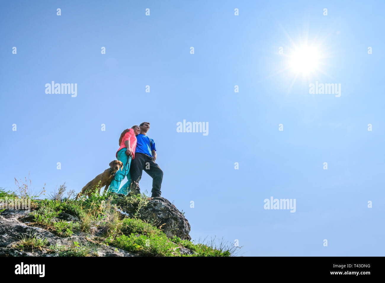 Paar beim Blick von einem hohen Felsen in der Hintergrundbeleuchtung Stockfoto