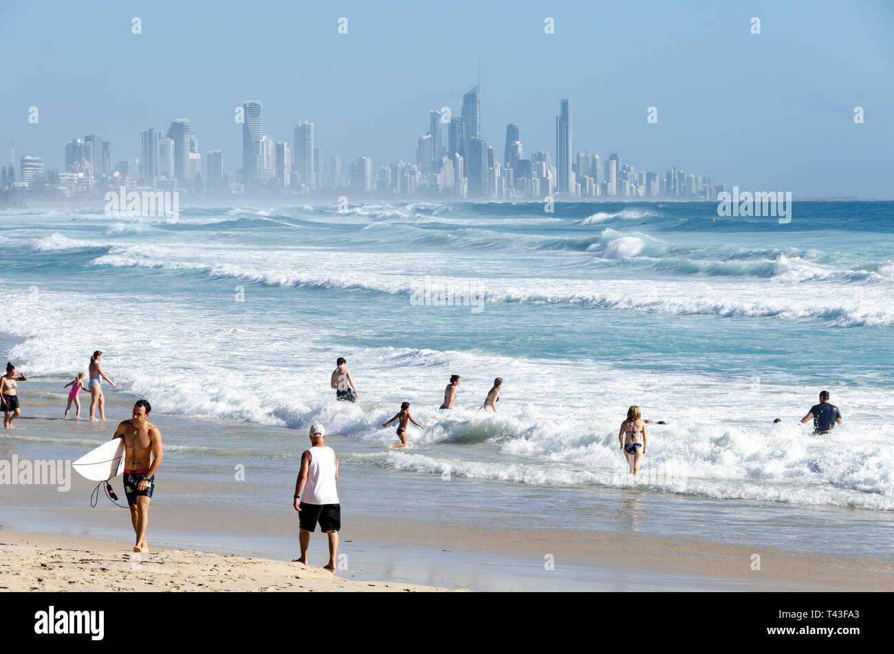 Die Leute am Strand, Schwimmen und Surfen, bei Burleigh Heads, Gold Coast, Queensland, Australien. Surfers Paradise in Distanz. Stockfoto
