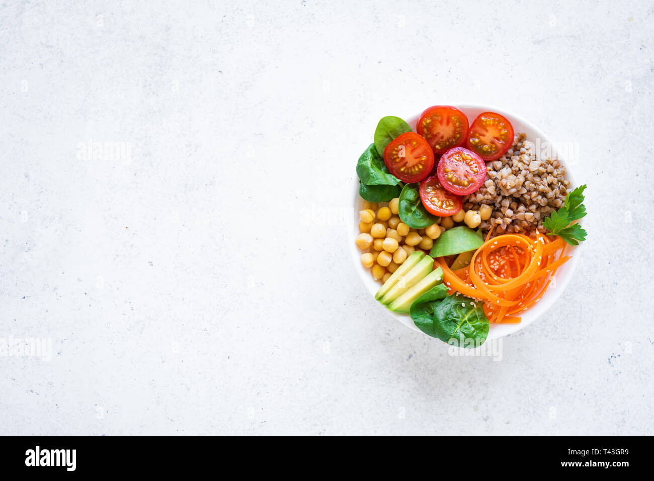 Buddha Schüssel Salat mit Buchweizen, Avocado, Karotten, Tomaten, Spinat, Kichererbsen auf Weiß. Gesunde vegetarische vegane Ernährung Essen, super Essen. Ansicht von oben, cop Stockfoto