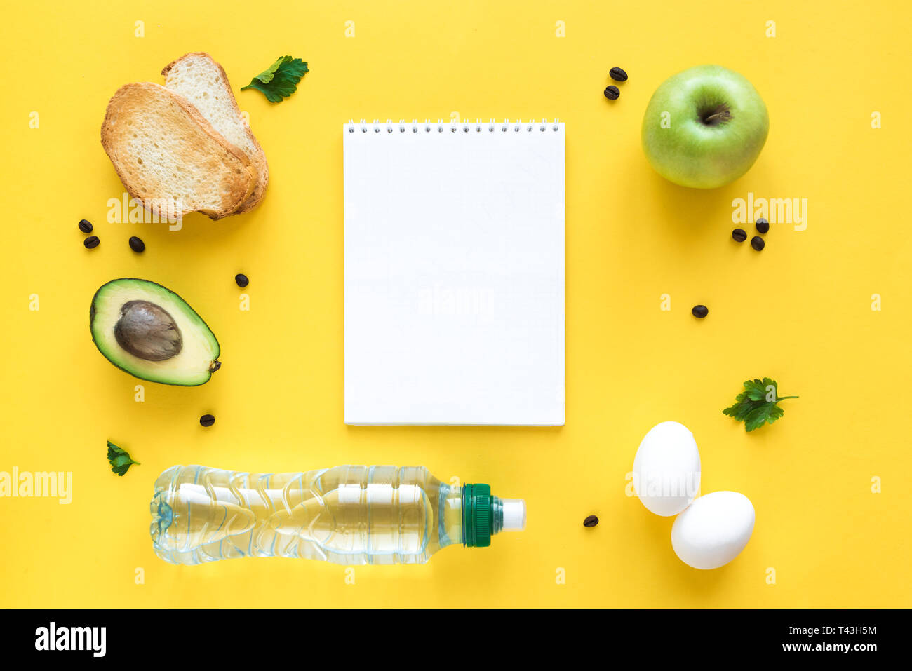 Avocado, Ei und Toast zum Frühstück und Notiz Buch auf gelbem Hintergrund, Ansicht von oben, kopieren. Gesunde Zutaten für das Frühstück - Eier, Brot, Avocado und Stockfoto