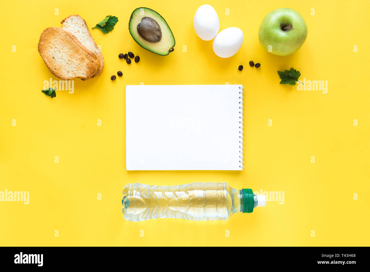 Avocado, Ei und Toast zum Frühstück und Notiz Buch auf gelbem Hintergrund, Ansicht von oben, kopieren. Gesunde Zutaten für das Frühstück - Eier, Brot, Avocado und Stockfoto