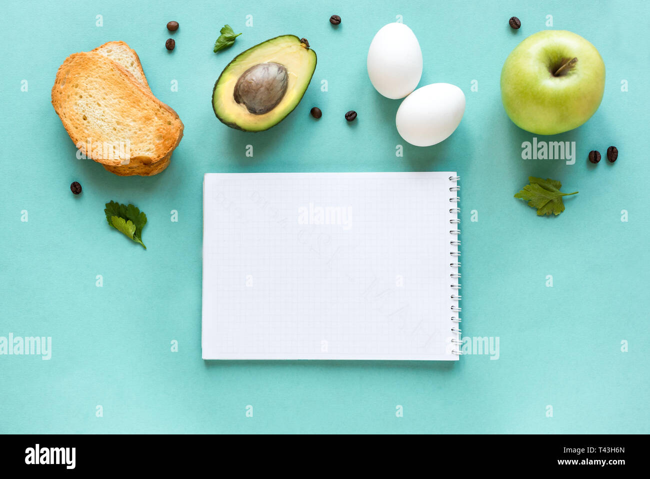 Avocado, Ei und Toast zum Frühstück und Notiz Buch auf blauem Hintergrund, Ansicht von oben, kopieren. Gesunde Zutaten für das Frühstück - Eier, Brot, Avocado und c Stockfoto