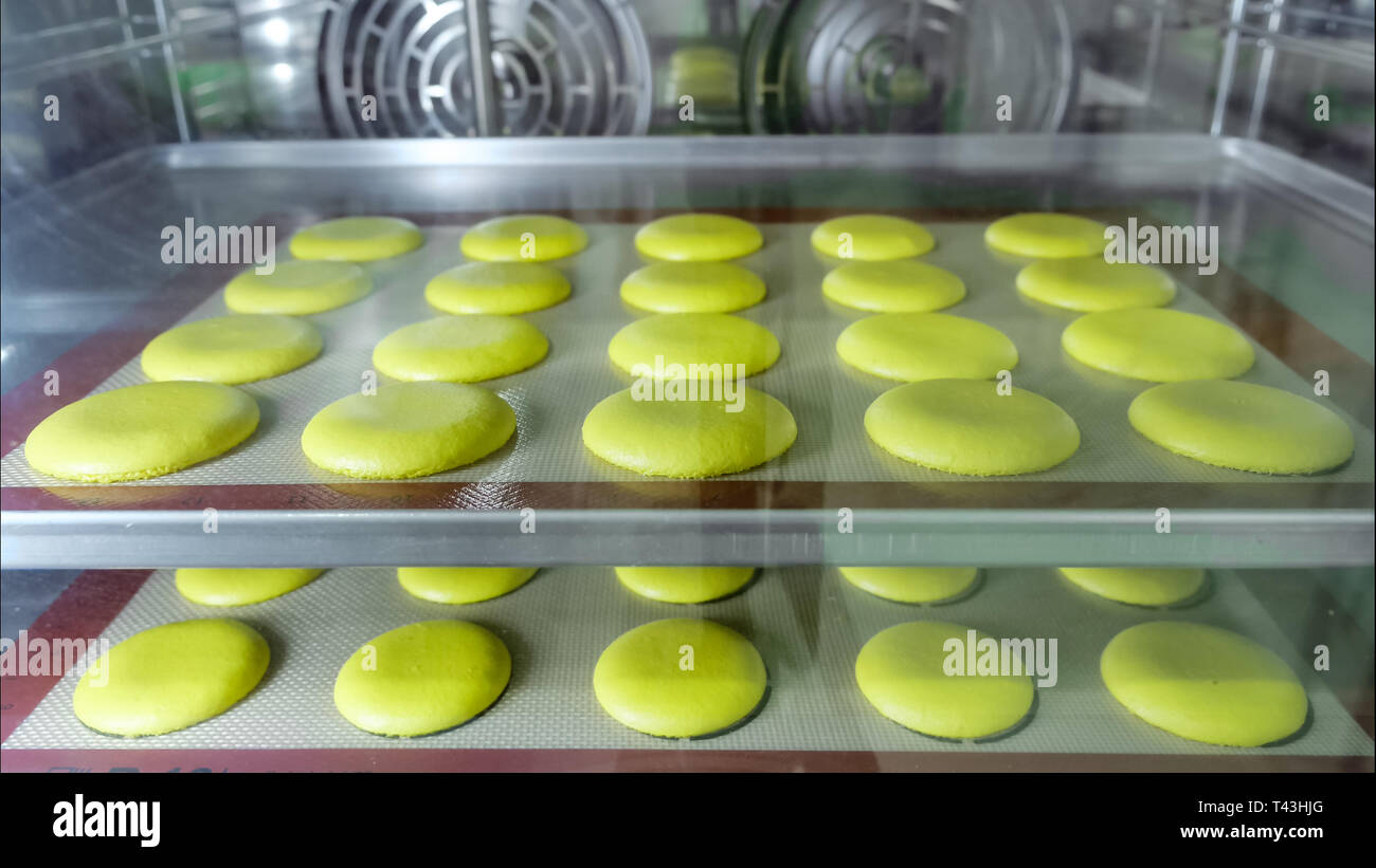 Makronen ist Backen im Ofen auf Schablone Silikon Matte auf Backblech. Stockfoto