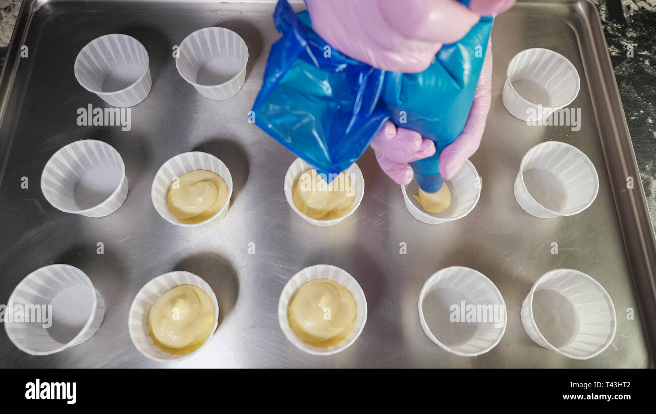 Konditor füllen Teig zum backen Muffins in Pappbechern auf einem Tablett  mit spritzbeutel.. Close-up Hände. top View Stockfotografie - Alamy