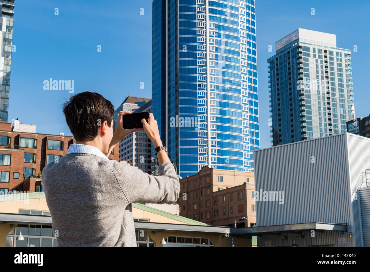 Ein junger Mann nimmt Fotos mit seinem Handy der Gebäude außerhalb Pike Market in Seattle. Stockfoto