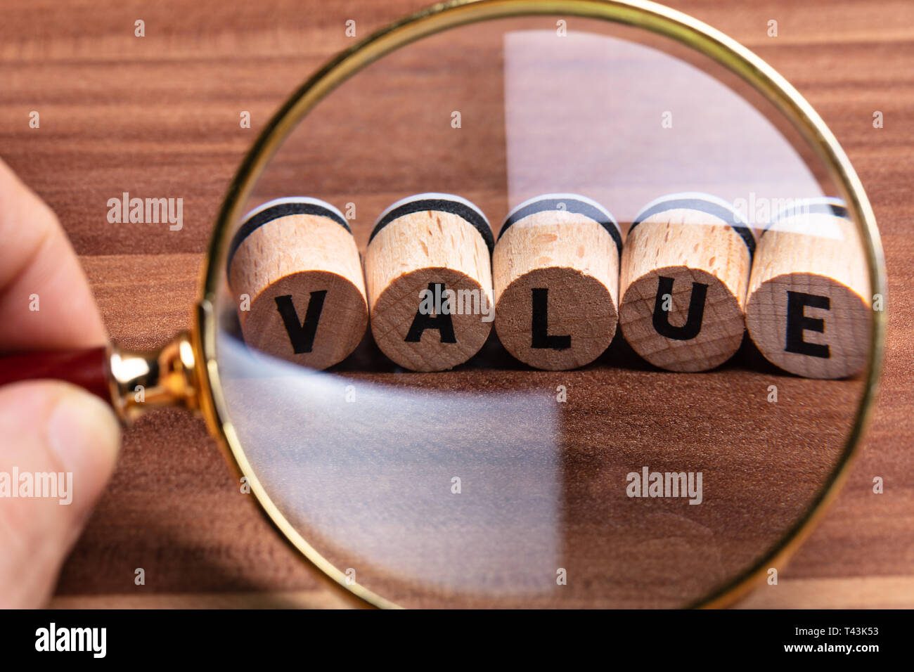 In der Nähe von des Menschen Hand mit Lupe über Holz Kork mit dem Wert Text Stockfoto