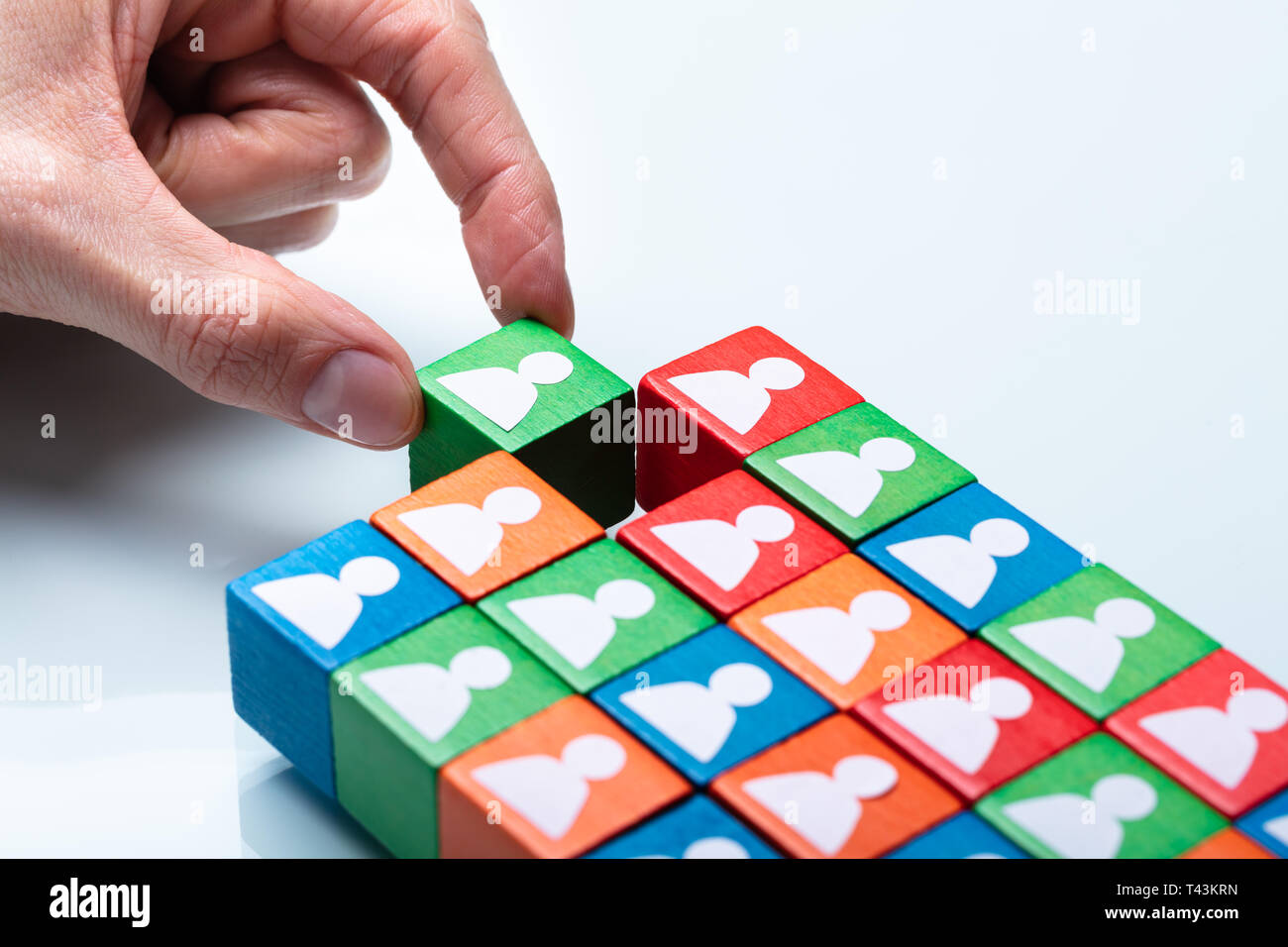 Der Unternehmer Hand grün Cubic Block in der Nähe der Mannschaft der Roten und Grünen Blöcke Stockfoto