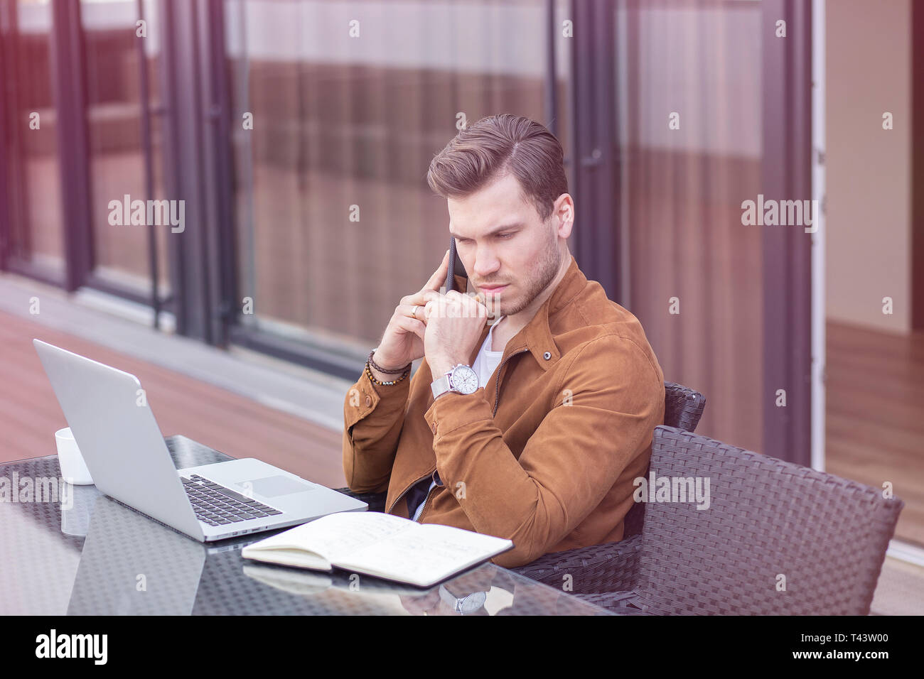 Hübscher junger Erwachsener Mann zu Hause arbeiten, Home Office mit Laptop und Smartphone Stockfoto