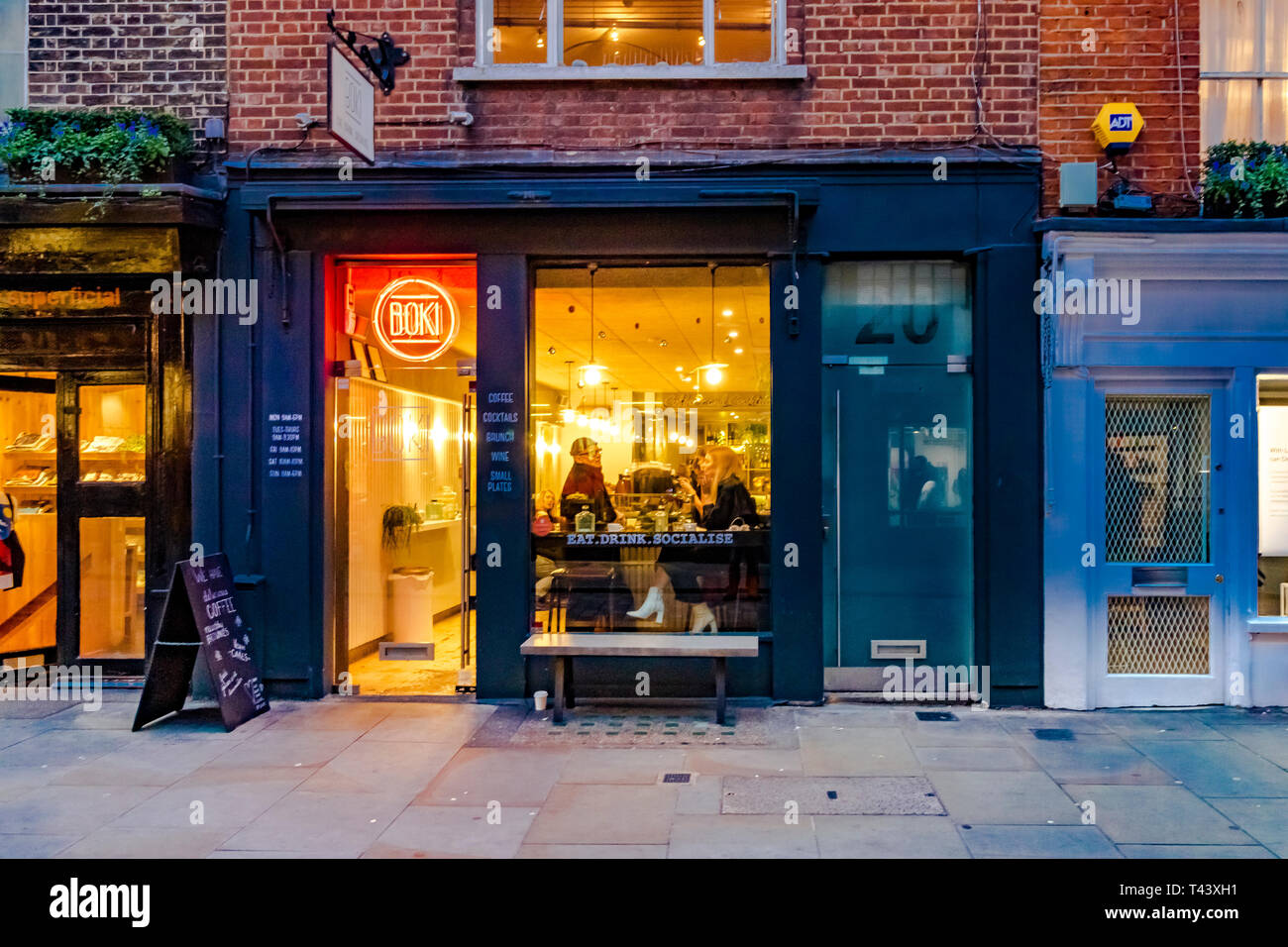 Eine Frau sitzt an einem Tisch am beleuchteten Fenster in Boki, einem unabhängigen Café in Seven Dials, London, Großbritannien Stockfoto