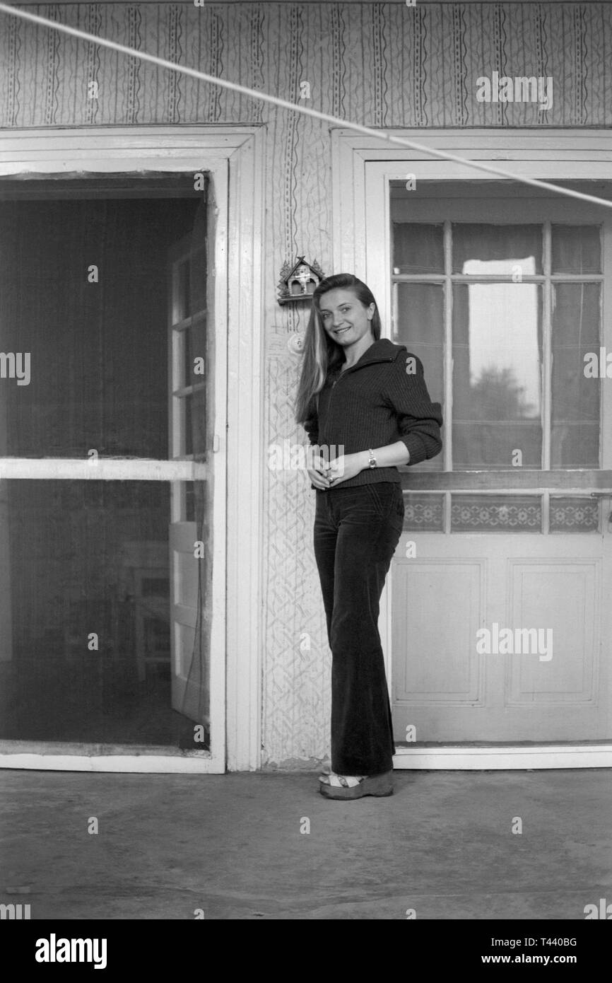 Lächelnden jungen Frau tragen Schlaghosen stehen auf der Veranda Ihrer traditionellen ungarischen Home 1960 Ungarn Stockfoto