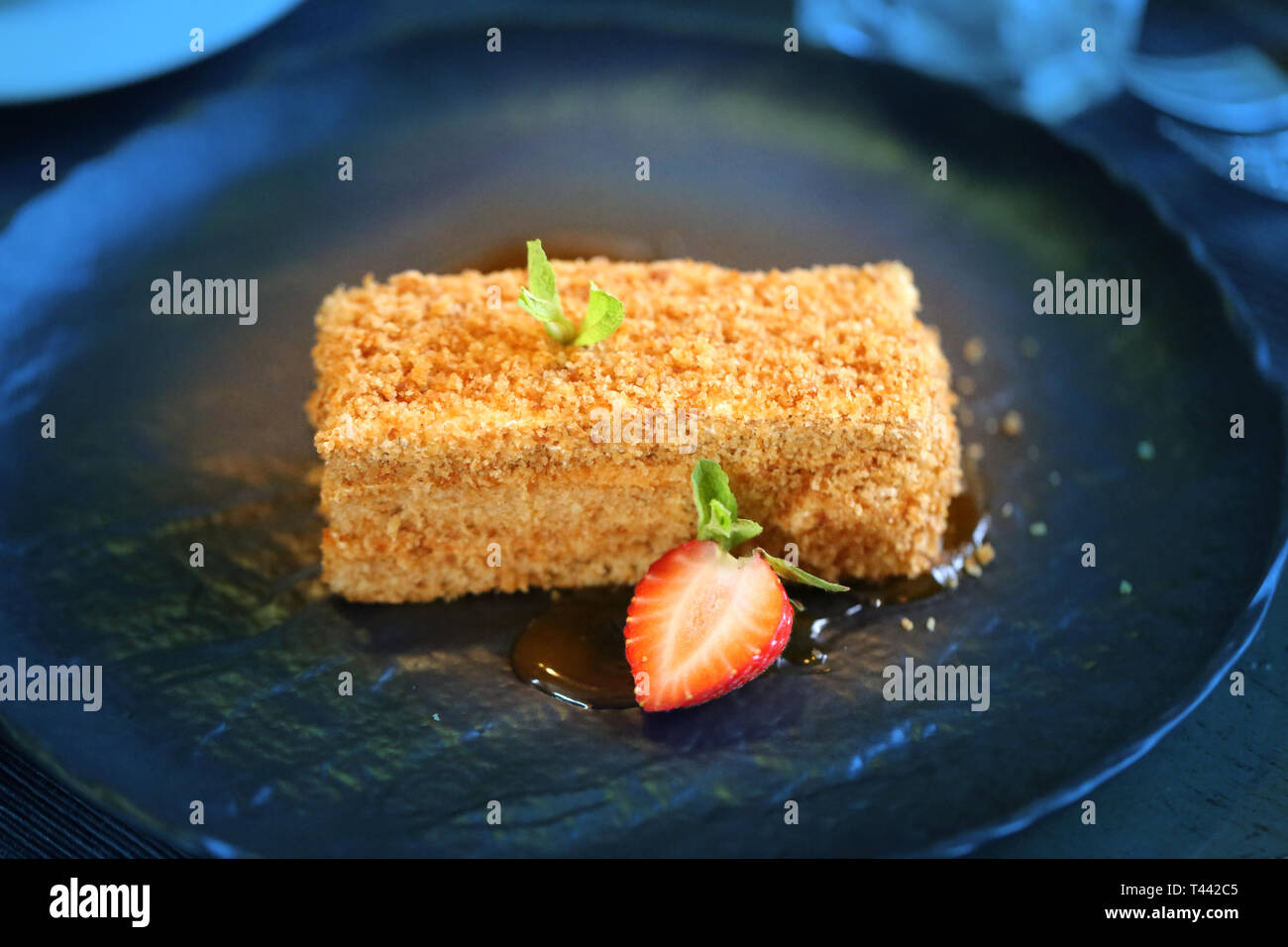Köstliche Kuchen mit Honig und Erdbeeren, die auf eine große schwarze Platte Stockfoto