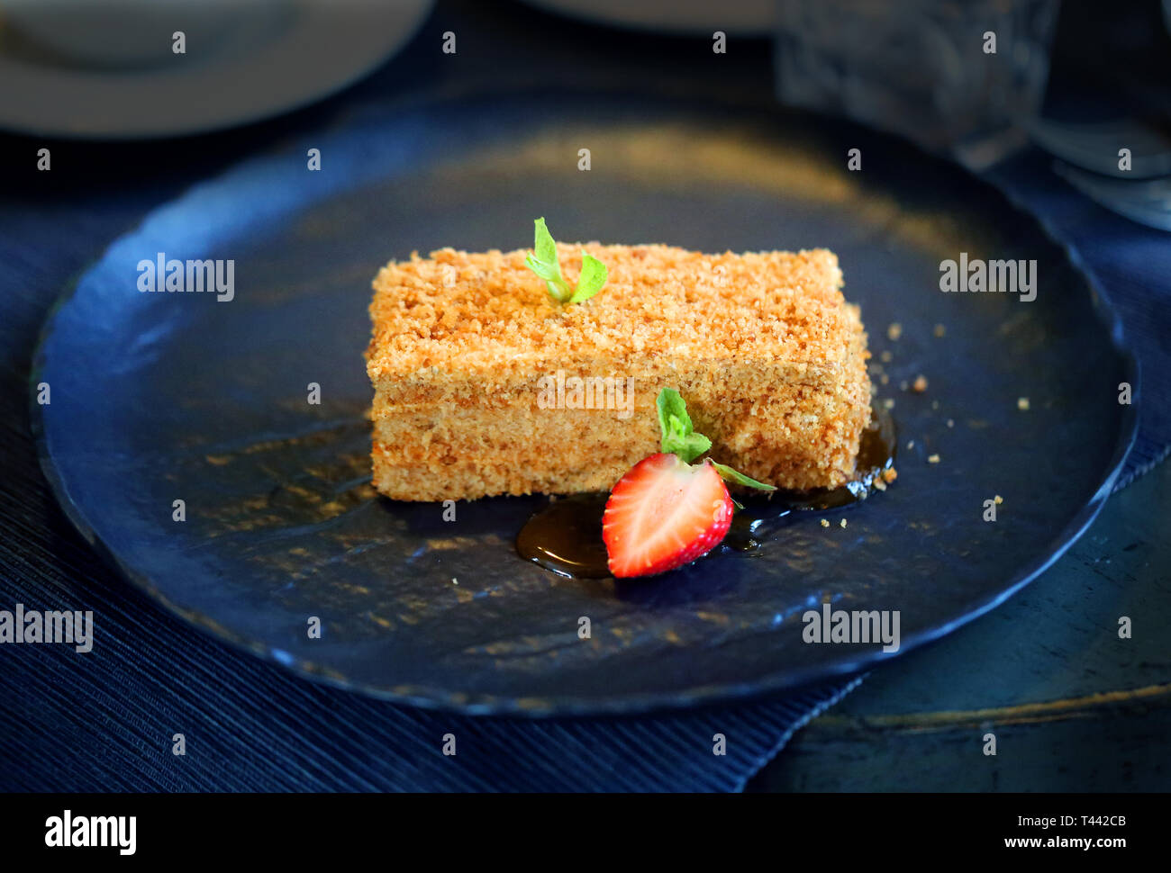 Köstliche Kuchen mit Honig und Erdbeeren, die auf eine große schwarze Platte Stockfoto