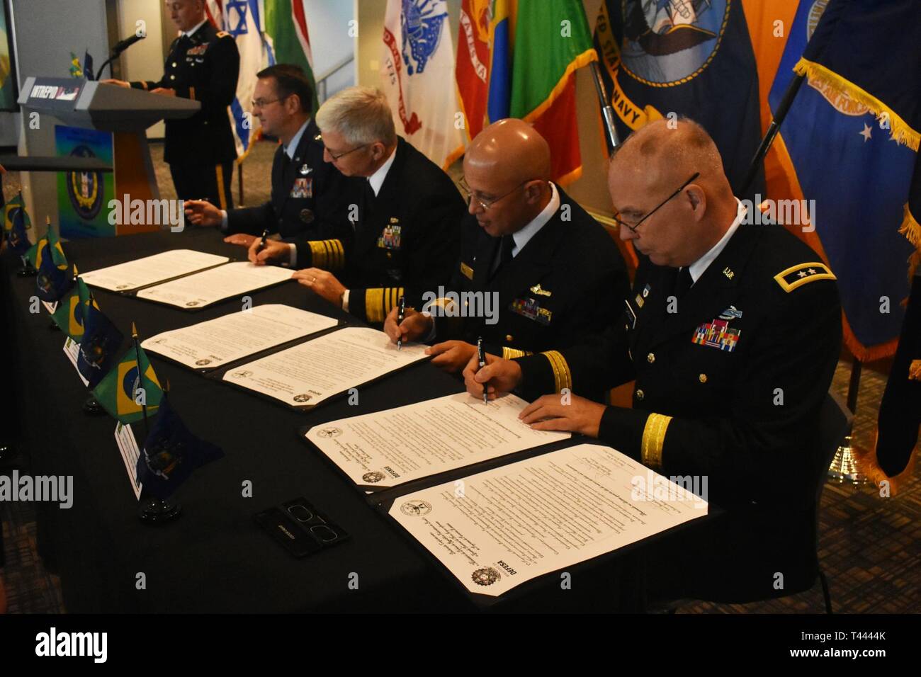 Leiter für internationale Angelegenheiten beim Brasilien Ministerium der Verteidigung, Konteradmiral Guilherme Da Silva Costa (Mitte rechts) und New York National Guard Adjutant Gen., Generalmajor Raymond Schilde (rechts), unterzeichnen eine Partnerschaft, auf die U.S.S. Intrepid, Manhattan, New York, 14. März 2019. Admiral Craig Faller, der Kommandant der United States Southern Command (Mitte links) und General Joseph Lengyel, Leiter der National Guard Bureau (ganz links) Auch an die Unterzeichnung fand. Die Partnerschaft zwischen der New Yorker Nationalgarde und Brasilien ist ein Verteidigungsministerium gemeinsame securit Stockfoto