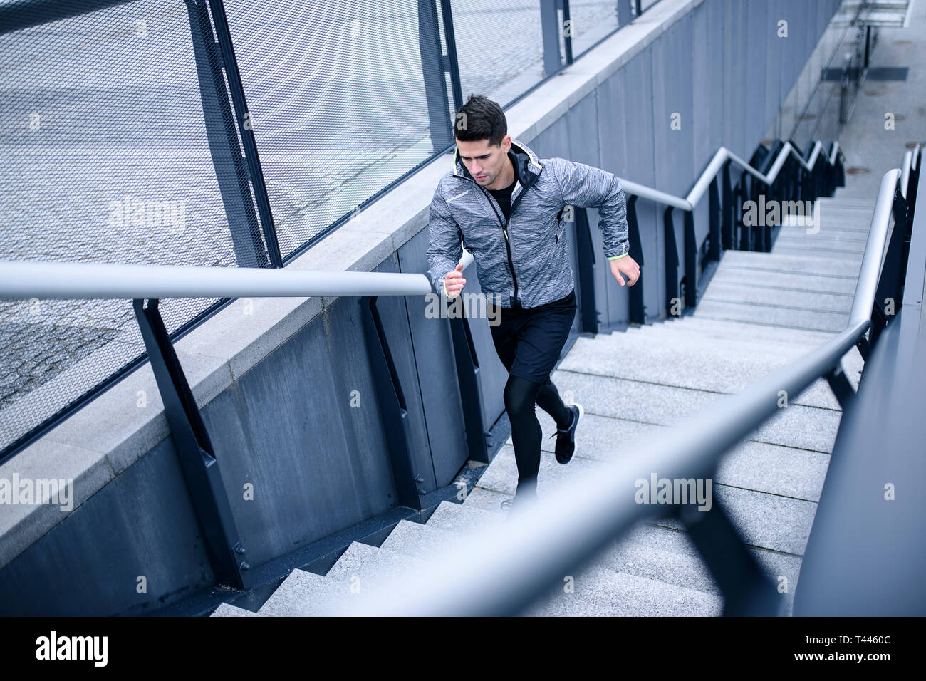 Blick von oben auf die jungen erwachsenen Sportler läuft die Treppe hinauf in den modernen städtischen Bereich. Konzept der Ziele zu erreichen. Stockfoto