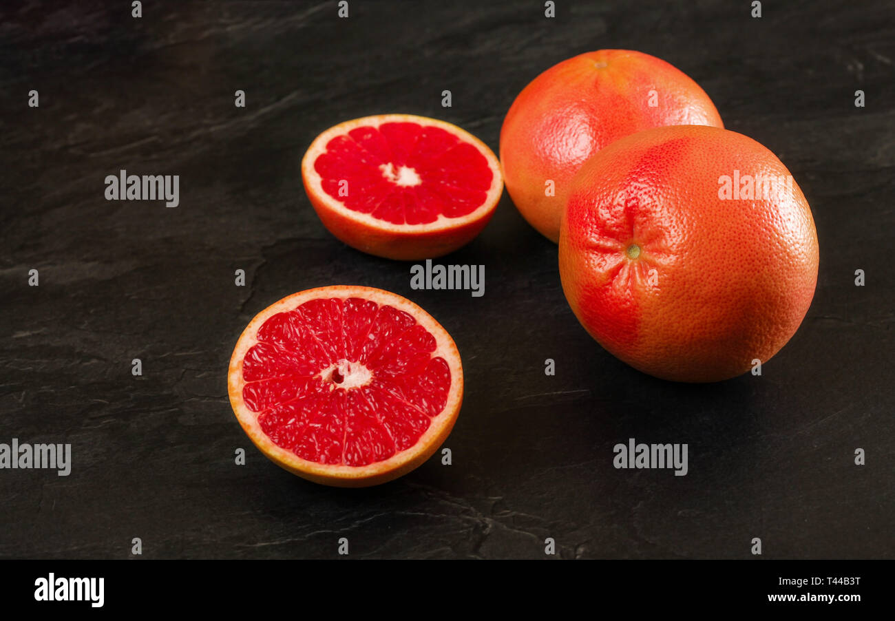 Rosa Grapefruits, einer Zitrusfrucht halbieren, auf schwarzem Schiefer board Stockfoto