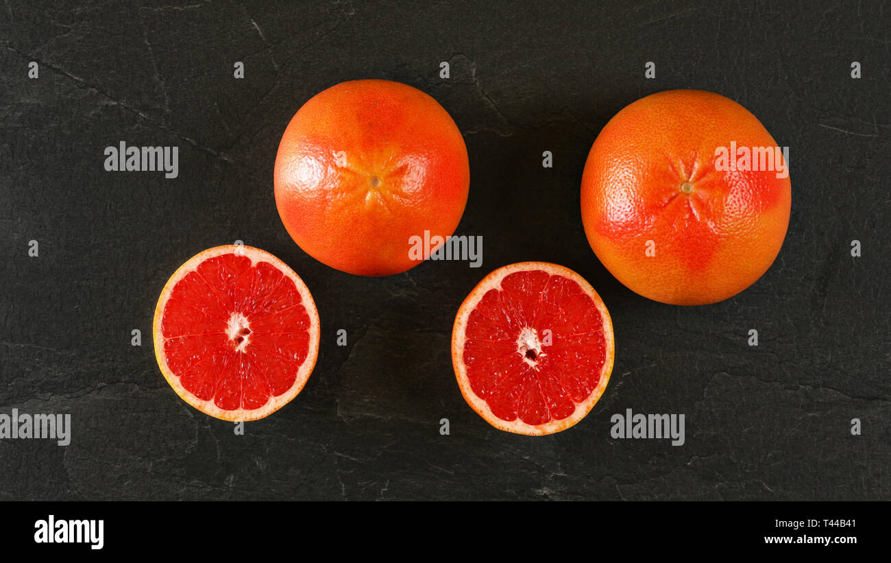 Flach Foto - grapefruits, halbiert, auf schwarzem Schiefer wie Board Stockfoto
