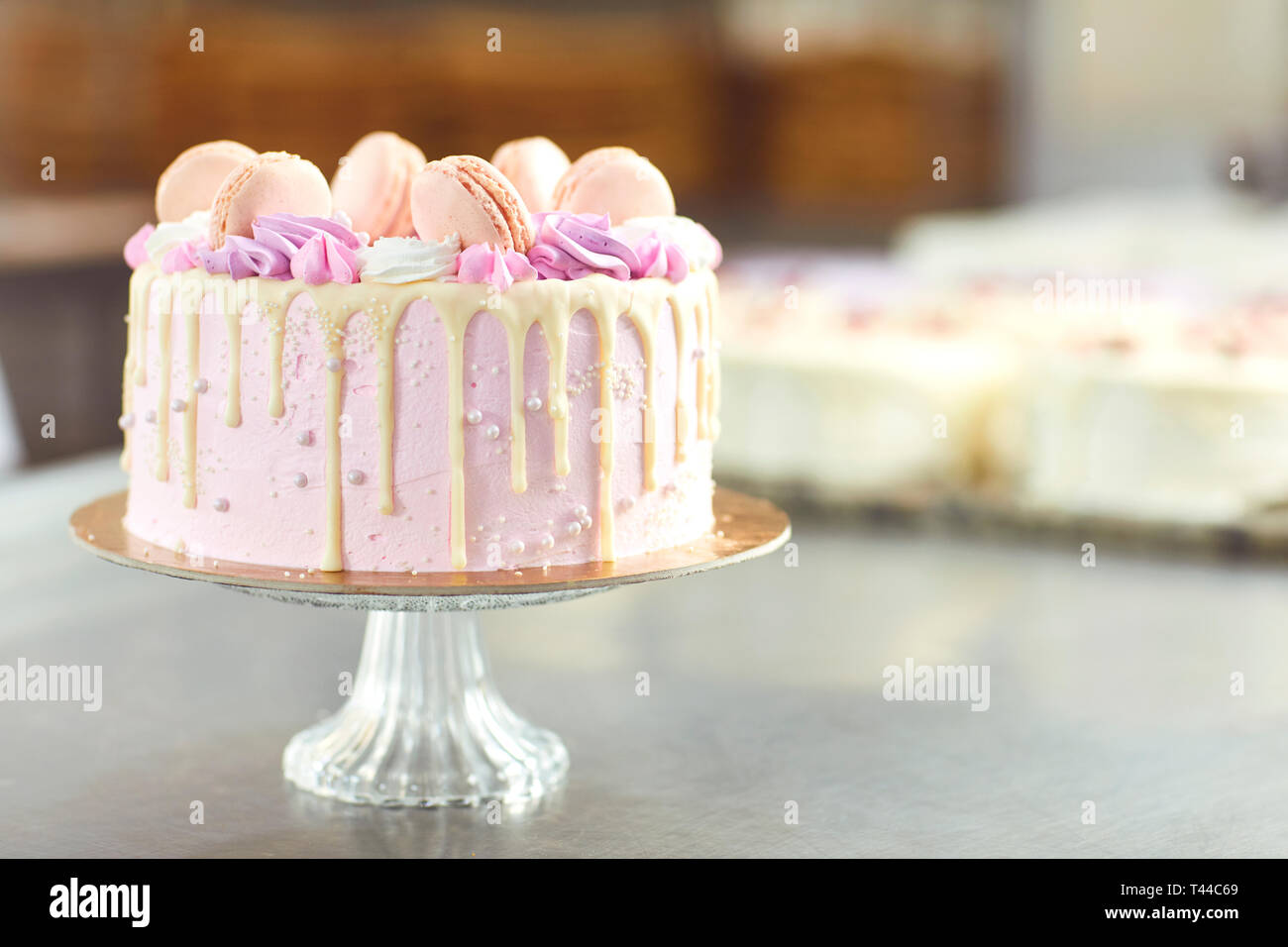 Rosa Kuchen mit Makronen auf dem Tisch eingerichtet. Stockfoto