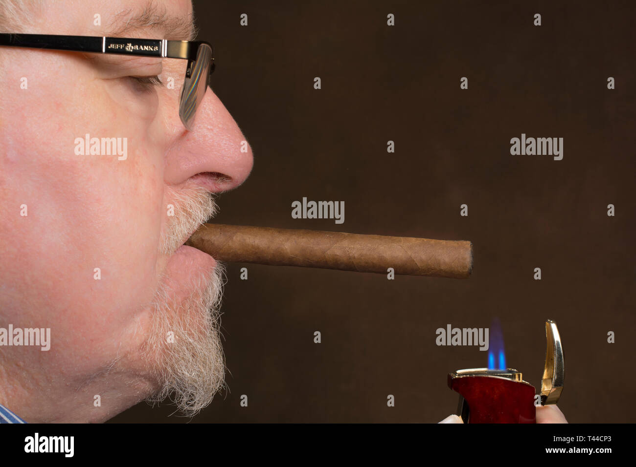 Ein Mann Beleuchtung eine Zigarre mit einem Zigarettenanzünder Stockfoto