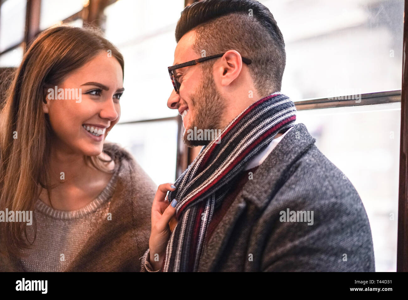 Glückliches Paar lachend, während sie einander im Bus - junge schöne Frau ihrem Freund durch Ziehen Schal neben ihr - Liebe, romantische Konzept Stockfoto