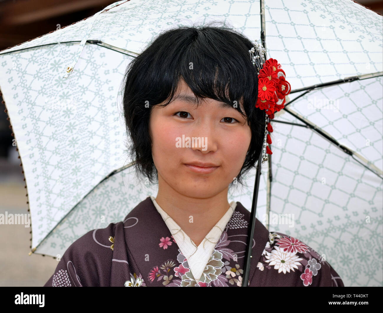 Junge japanische Frau mit Regenschirm posiert für die Kamera an einem regnerischen Tag. Stockfoto