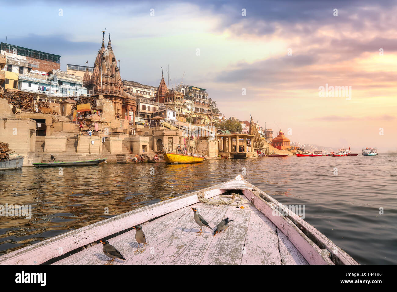 Varanasi alten Indien Stadt Architektur auf, die von einem Boot auf dem Fluss Ganges mit Blick auf Zugvögel mit stimmungsvollen Sonnenuntergang Himmel gesehen Stockfoto