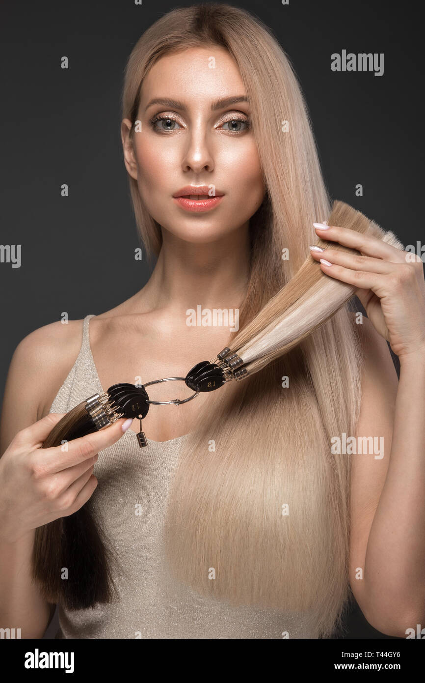 Schöne blonde Mädchen mit einem perfekt glatte Haare, klassische Make-up mit einer Palette für Hair Extensions in den Händen. Schönheit Gesicht. Stockfoto