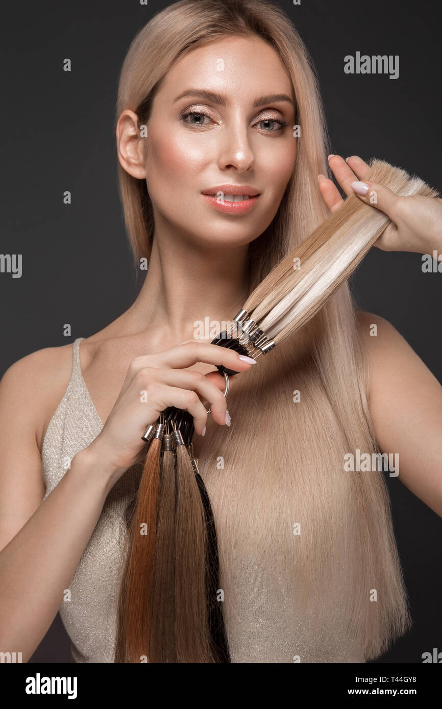 Schöne blonde Mädchen mit einem perfekt glatte Haare, klassische Make-up mit einer Palette für Hair Extensions in den Händen. Schönheit Gesicht. Stockfoto